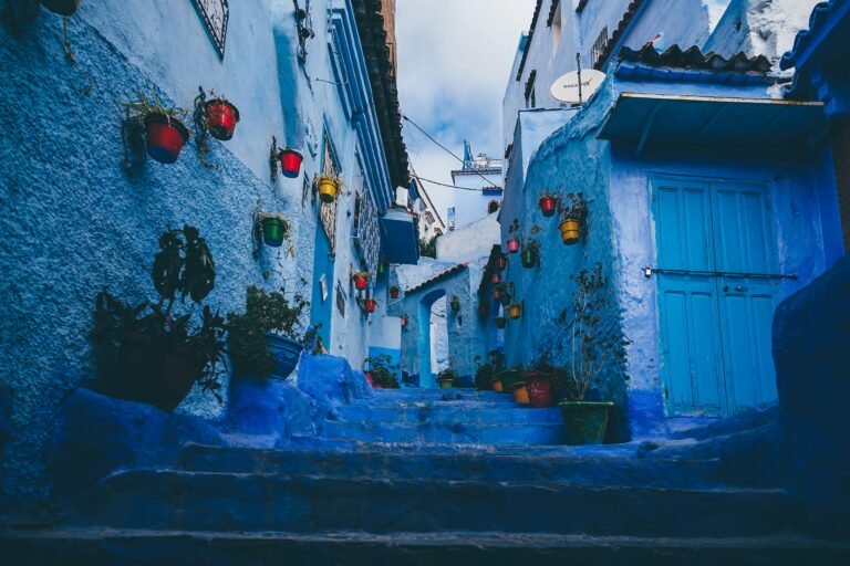 Colorful pots line the blue-washed walls of a narrow alley in Chefchaouen, Morocco.